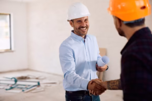 Happy building contractor shaking hands with a worker at construction site.